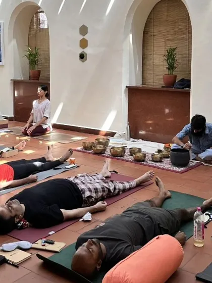 A sound healing session in progress. Participants are in Savasana, absorbing the restorative vibrations of the singing bowls. This is a practice of deep listening and letting go.
