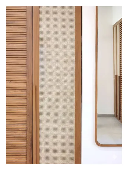 A detail of a wardrobe combining louvered wood and cane panels. This pairing of textures is not just for aesthetics; it provides ventilation while maintaining visual lightness, a principle I apply to make furniture both beautiful and practical.
