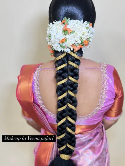 A unique and modern take on a traditional braid. This fishtail braid is accented with a gold ribbon and topped with a fresh flower veni, creating a stylish look for any wedding event.