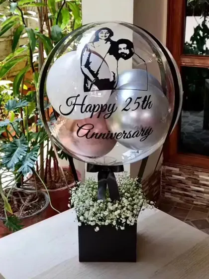 For a 25th anniversary, we created this custom photo balloon bouquet. We printed a caricature of the couple directly onto the balloon, which sits above a classic box of baby's breath for a truly personalized and memorable gift.