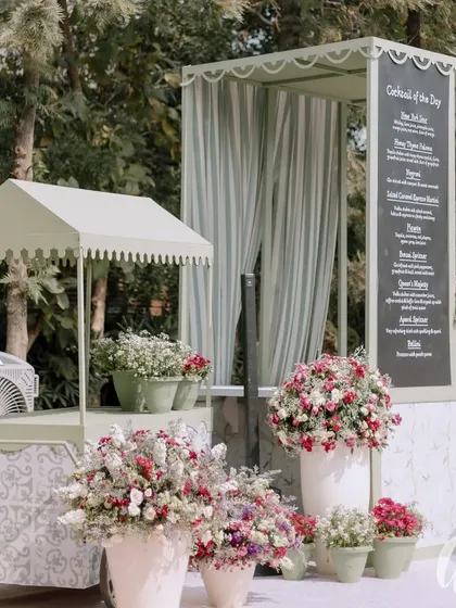 We designed a charming cocktail bar with a matching floral cart. The sage green structures with scalloped awnings and custom-printed panels perfectly complement the garden theme.