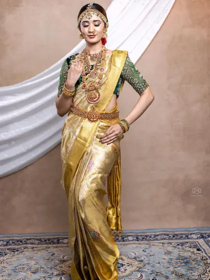 A complete bridal muhurtham look featuring a golden tissue saree paired with a rich green velvet blouse with heavy embroidery.