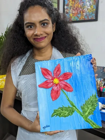 A participant proudly holding her finished texture painting of a flower. The raised texture makes the artwork pop and adds a unique tactile element.