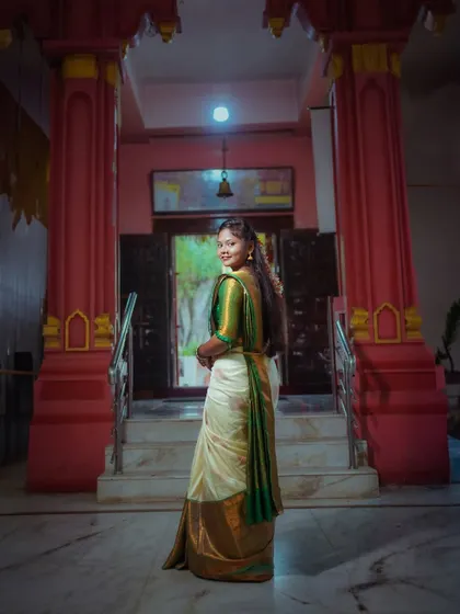 A beautiful portrait of a woman in a traditional South Indian saree at a temple. The shot from behind as she looks back creates a graceful and classic pose.