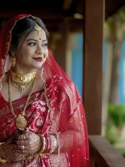 An elegant portrait of our Bengali bride, Rajashree. We captured her in a moment of quiet contemplation, her traditional red saree and gold jewelry shining in the soft, natural light.