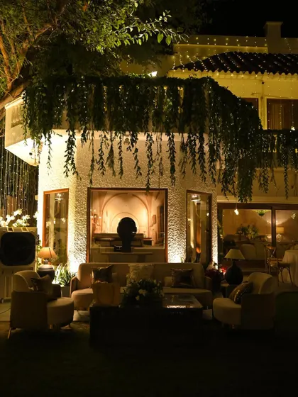 An outdoor lounge area designed for a cozy gathering. We used comfortable seating and hung lush greenery from the balcony above to create a sense of intimacy and connection with nature.