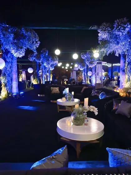 Another perspective of the expansive lounge, showing the deep blue velvet sofas and the enchanting glow from the illuminated trees and hanging lights.
