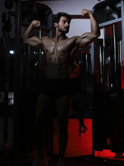 A dark and moody shot of a front double biceps pose. This highlights the shadows and contours of the muscles, showing a different side of physique photography.