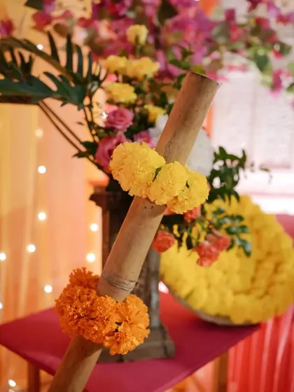 A close-up of a Mehendi decor detail, showing the vibrant colors of marigolds against a backdrop of pink and orange fabrics.