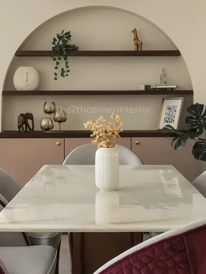 A closer view of the dining setup, with plush velvet chairs in a rich magenta hue set against a neutral backdrop. The arched crockery unit provides both storage and a beautiful display area.