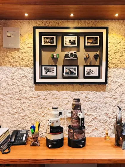 A close-up of the custom desk in the home office, featuring a textured wall backdrop and a curated display of photography equipment and personal mementos.