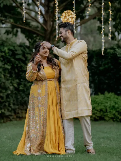 A sweet moment where the groom affectionately touches the bride's forehead during their Haldi portrait session.