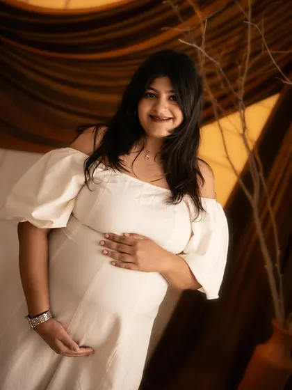 A beautiful close-up shot focusing on the mother-to-be's happy smile and the lovely details of her white dress.