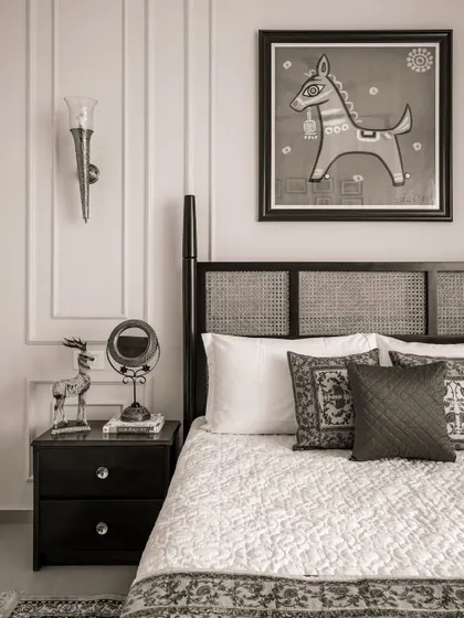 From our 'Heritage Hue' project, this bedroom showcases a classic aesthetic. It features a custom-made bed with a cane headboard, a dark wood bedside table, and traditional Indian artwork.