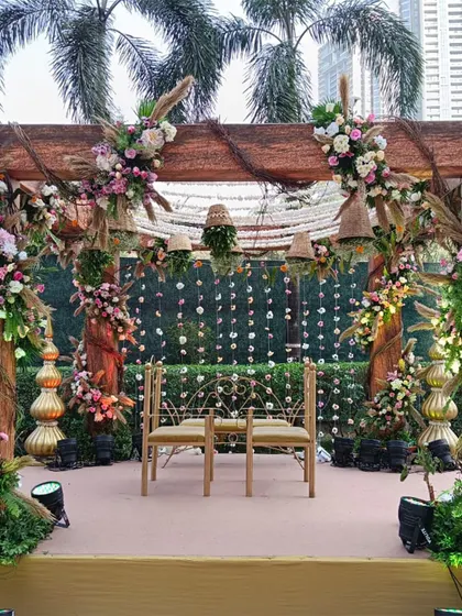 A front view of the rustic wooden mandap, showcasing the seating arrangement for the couple against a backdrop of hanging floral strings.