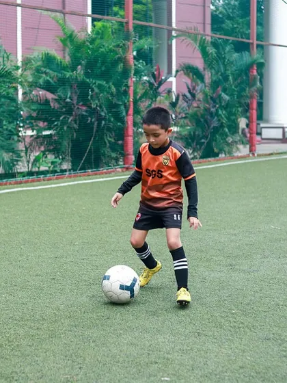 A young player practicing his dribbling skills around cones. We use age-appropriate drills to develop coordination and technique from the very beginning.