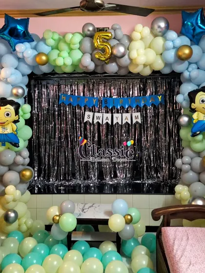 A Chota Bheem theme for a 5th birthday home party, featuring a balloon arch with character foil balloons against a shimmer curtain.