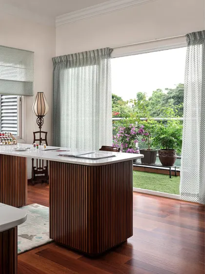 The studio opens onto a balcony, providing natural light and fresh air. The fluted wood texture on the island base is a recurring motif throughout the home.