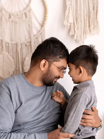 A father and son share a moment of connection, forehead to forehead. This intimate and tender pose is a beautiful way to show the strong bond between them.