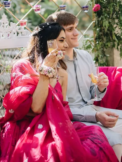 A relaxed moment for the couple during their Haldi. The bride's floral hathphool is a perfect accessory for this vibrant event.