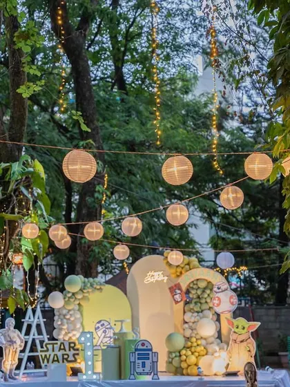 May the force be with you. A magical outdoor Star Wars-themed party, complete with characters like Yoda and R2-D2, set against a backdrop of lush greenery and string lights.