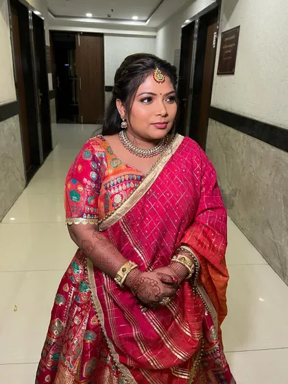 A lovely client ready for a wedding celebration in a vibrant pink and orange outfit, with makeup kept subtle and fresh.