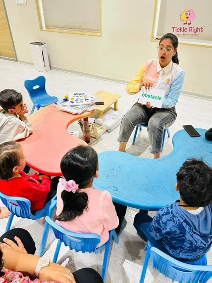 A trainer uses a word card to teach a new concept, and the children's expressions show their complete engagement. We make vocabulary building an exciting and interactive experience.