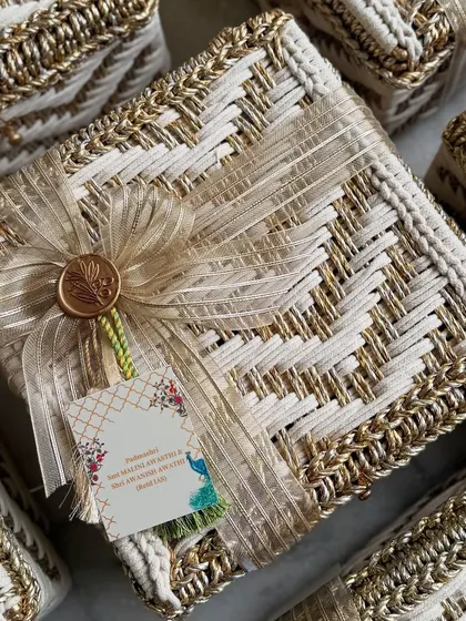 A close-up of the engagement invitation hamper for Rinku Singh and MP Priya Saroj. The handwoven box is tied with a gold ribbon and finished with a custom wax seal, reflecting pure opulence.