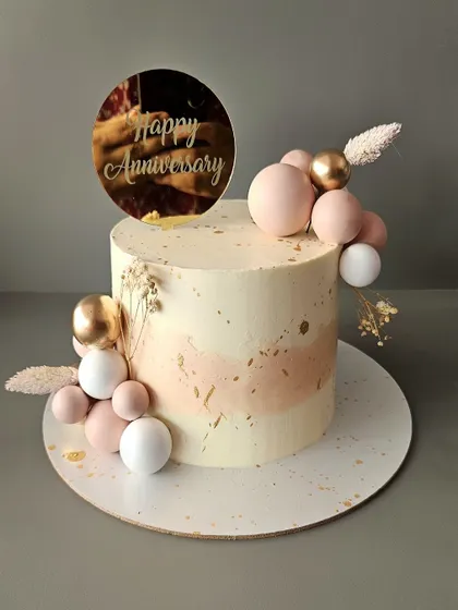 Grace. A simple and elegant pineapple anniversary cake in dusky pink and white, decorated with chocolate spheres and dried botanicals.