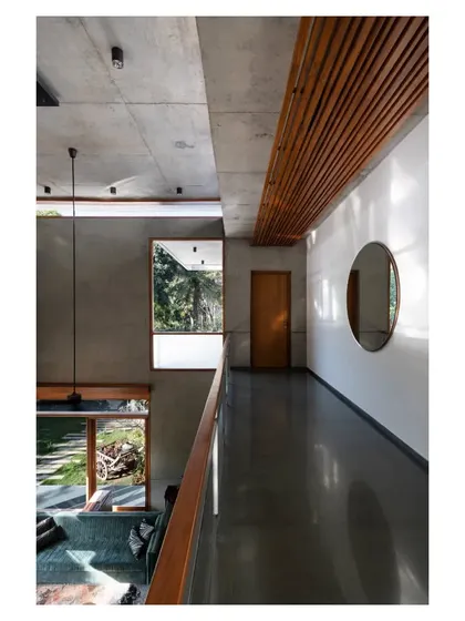 The bridge-like corridor on the upper floor, with its slatted wood ceiling, offers dramatic views down into the living areas and out into the garden.