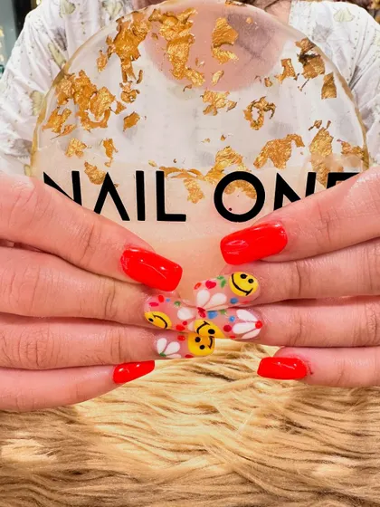A close-up of the smiley face and daisy nail art. The clear base on the accent nails makes the colorful designs pop, showcasing our skill with fine-line brushwork.