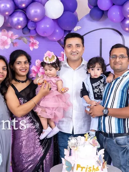 A lovely family photo in front of a purple floral birthday setup.