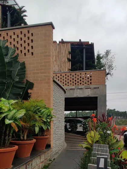 Another view of the Sunyata Hotel's exterior, showing the blend of exposed brick, stone, and bamboo screens, all softened by abundant greenery.