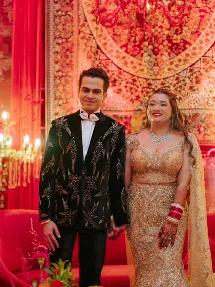 The happy couple at their red and black themed reception. The groom's embellished tuxedo and the bride's golden lehenga were pure glam.