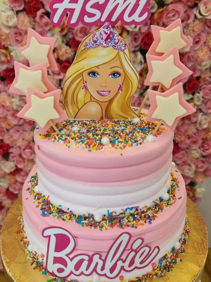 Come on Barbie, let's go party! This two-tiered Barbie cake features a pink and white ombre design, colorful sprinkles, and iconic Barbie branding, perfect for a themed birthday.