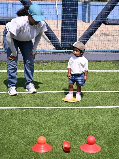 A teacher encourages a toddler as she stands on a balance disc, ready for her next challenge.