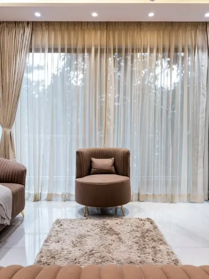 A view from the sofa in a modern living room, looking out through sheer curtains. The space is designed for comfort and relaxation, with a soft color palette and plush, contemporary furniture.
