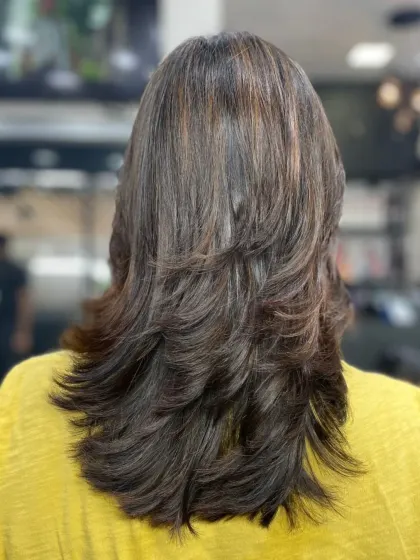 A classic multi-layered or feather cut from the back, showing how layers can create shape and reduce weight in thick hair.