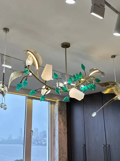 This close-up highlights the intricate details of the custom-designed chandelier, where golden birds appear to fly among glass leaves, creating a sense of movement and artistry.