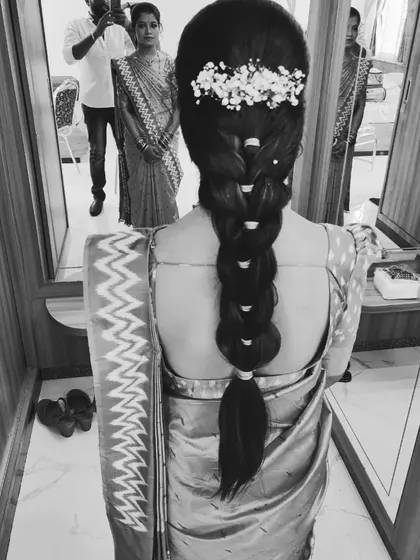 A black and white photo of a bubble braid adorned with baby's breath, showing the timeless structure of the style.