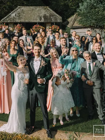 The happy couple poses with all their guests for a celebratory group photo, showcasing the warmth and joy of their intimate wedding.