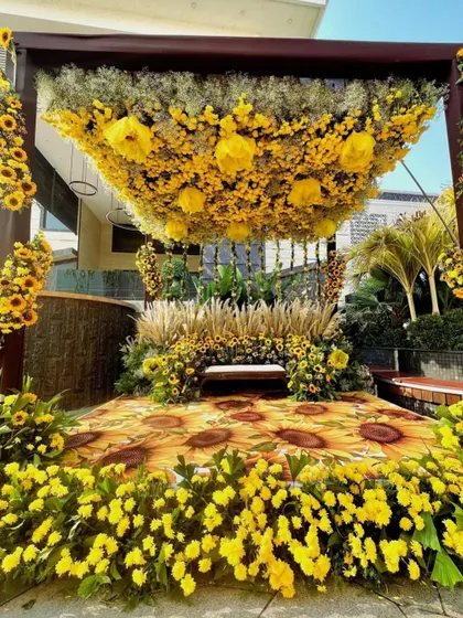 A stunning sunflower-themed Haldi mandap. The setup is overflowing with sunflowers, from the overhead canopy to the floor, creating a vibrant and immersive experience.