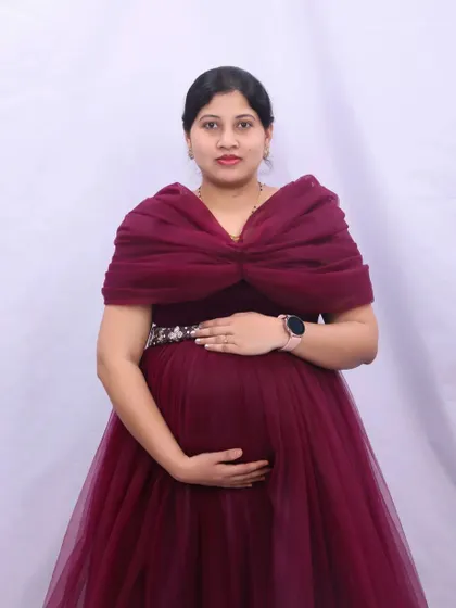 A classic maternity pose in a maroon gown with a dramatic wrap top. The plain white background provides a clean and bright look for your portraits.