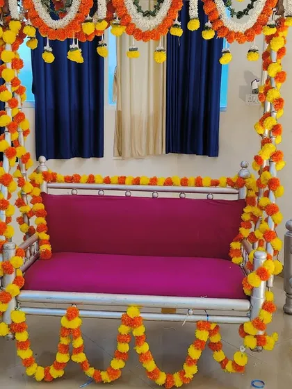 A traditional jhula (swing) decoration for a baby shower, beautifully adorned with yellow and orange marigold garlands for a classic look.