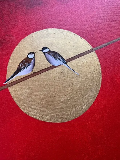 A close-up of the two birds, showing the detail in their feathers and the texture of the golden moon.