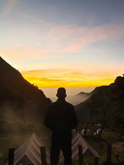 A silhouette of a trekker watching the sunrise, capturing a moment of quiet contemplation.