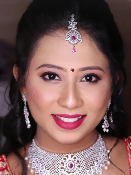 A close up of a stunning reception look. The focus is on the sparkling diamond jewelry, complemented by a shimmery pink eyeshadow and a bright, happy smile.