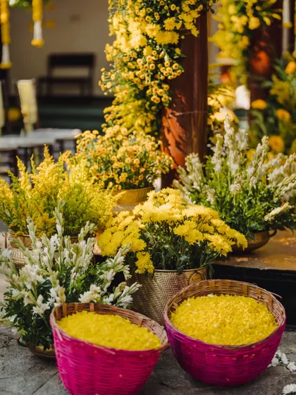 A detail shot of the Haldi decor, featuring baskets of yellow petals and vibrant pink woven baskets, ready for the guests to use in the ceremony.