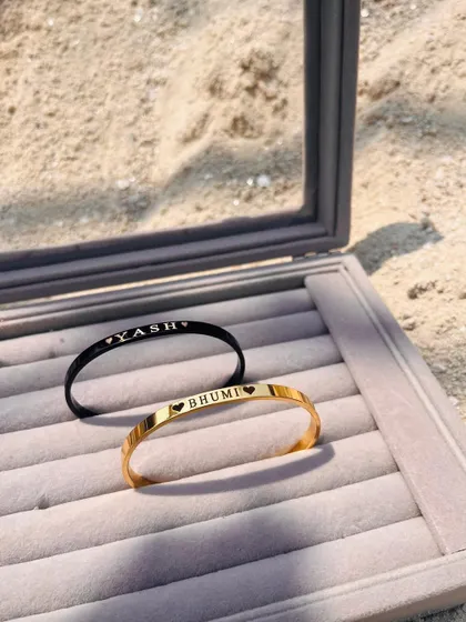 His and hers. This photo shows a pair of personalized Kadas in a jewelry box, one in black for 'Yash' and one in gold for 'Bhumi', ready to be gifted.