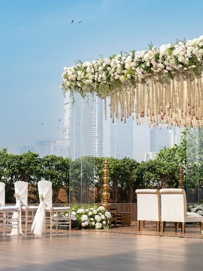 The mandap set against the Mumbai skyline, showing how we integrate urban backdrops with elegant decor. The transparent pillars ensure the city view remains a part of the scenic design.